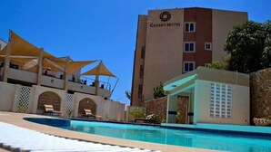 Un hotel con zona de piscina, incluyendo sillas de descanso y sombrillas.