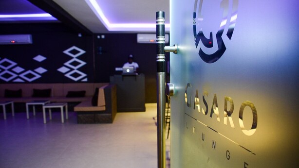 Un interior moderno con una recepción, zona de estar y un logotipo destacado en la pared.