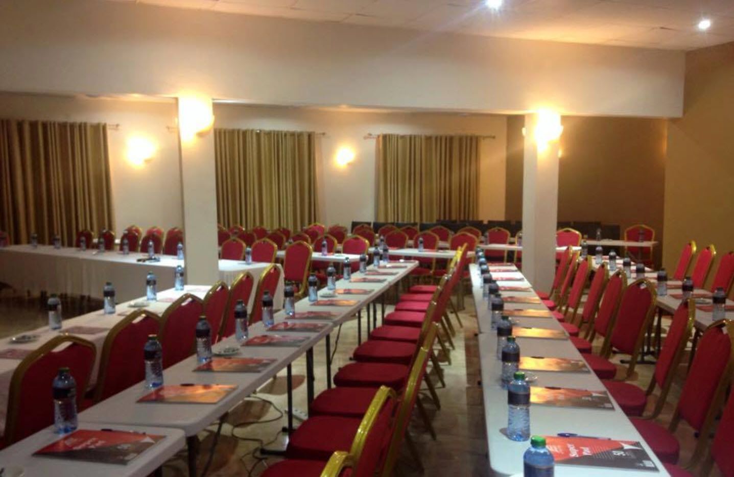 A conference room with rows of tables and chairs, equipped with water bottles and nameplates.