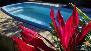Piscina con borde de piedra y follaje rojo en primer plano.