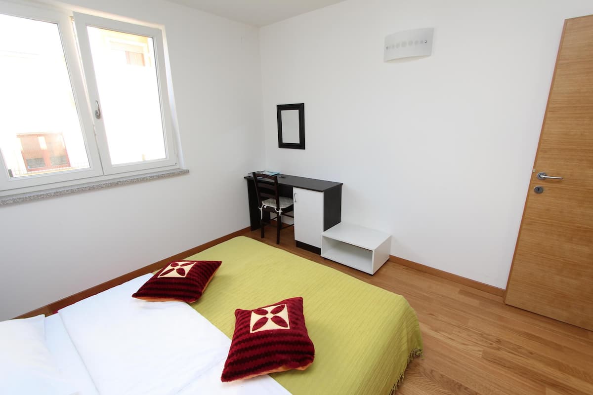 A bedroom with a bed, a desk, and a chair.