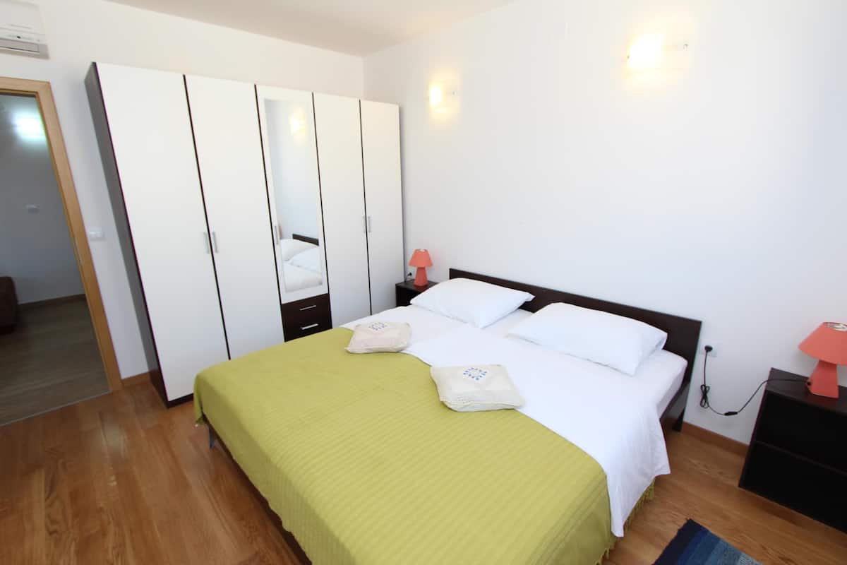 A bedroom with a bed, a wardrobe, a nightstand, and a lamp.