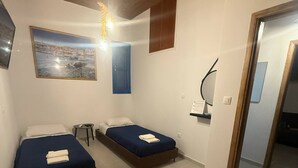 A room with two beds, a wooden ceiling, a painting, and a desk with a chair. - Occasus Room (Halki)