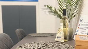 A table with a woven placemat, a bottle of liquor, a small bag, and a plant. - Occasus Room (Halki)