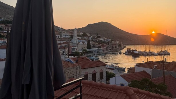 A coastal town at sunset with buildings and boats by the water. - Occasus Room (Halki)