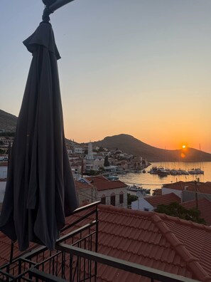 Une ville côtière au coucher du soleil, avec des bâtiments et des bateaux au bord de l’eau.