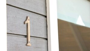 A wooden house number '1' mounted on a siding wall. - Vík Cottages (Vik I Myrdal)