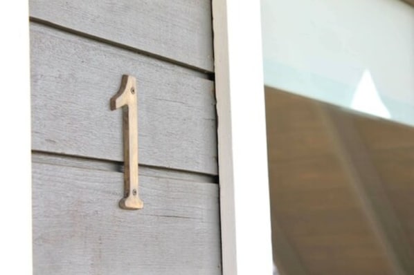 Número de casa de madera '1' fijado a un revestimiento de pared.