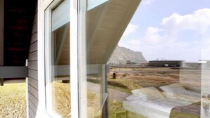 A modern building with a large glass window and a view of a mountainous landscape. - Vík Cottages (Vik I Myrdal)