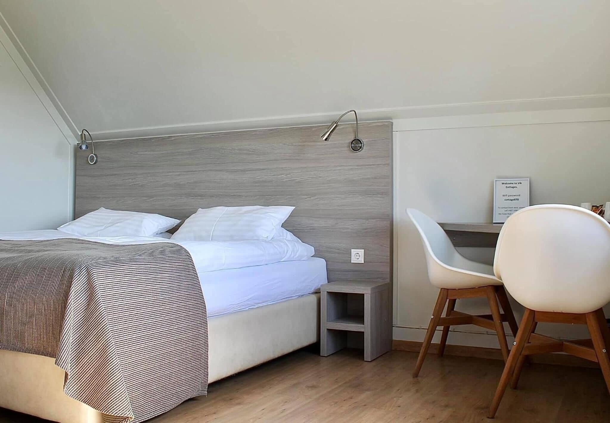 Une chambre à coucher comprenant un lit, une table de chevet, une chaise et un panneau indiquant le mot de passe du réseau Wi-Fi.