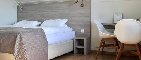 Une chambre à coucher comprenant un lit, une table de chevet, une chaise et un panneau indiquant le mot de passe du réseau Wi-Fi.