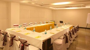 A conference room with a long table, chairs, water bottles, and a whiteboard. - Hollyhocks Residency (Gurugram)