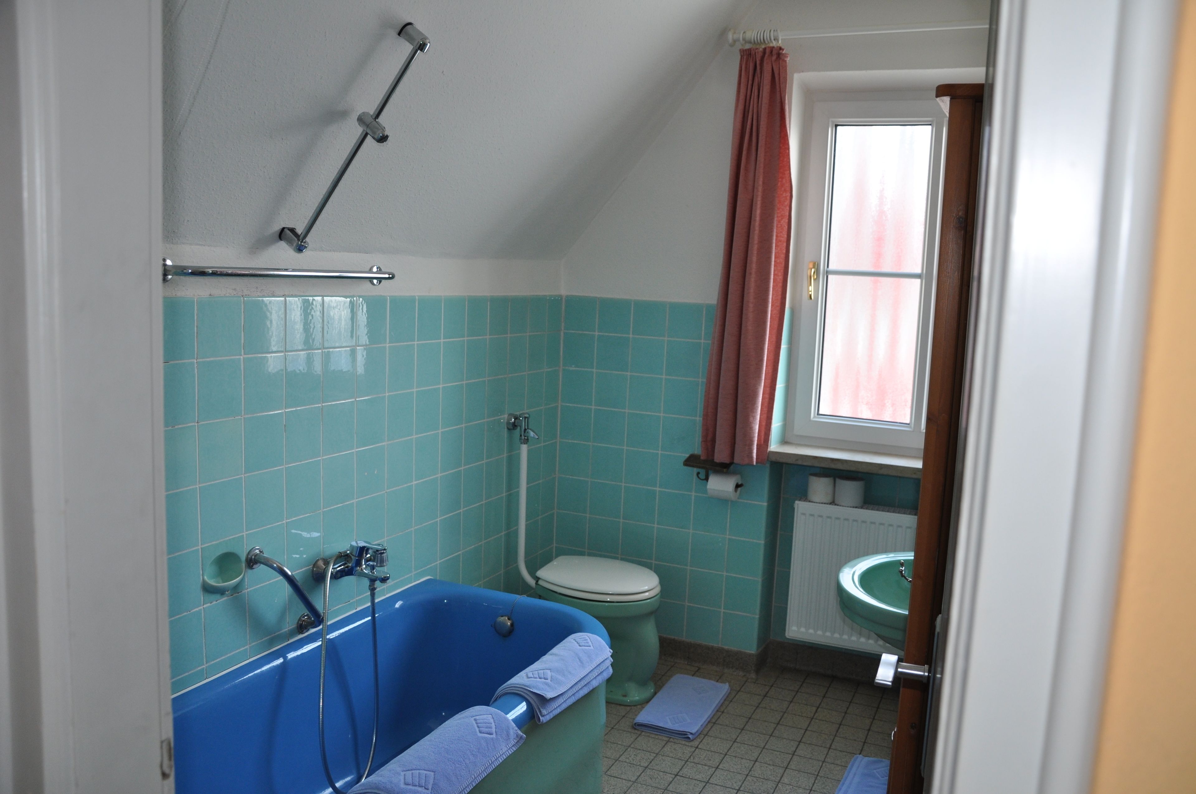 Un baño con una bañera azul, un inodoro y un lavabo.