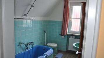 Un baño con una bañera azul, un inodoro y un lavabo.