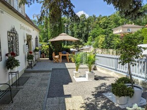 A courtyard with a patio table and chairs, surrounded by potted plants and a fence. - Pension Haus Gertrud (Donauwoerth)