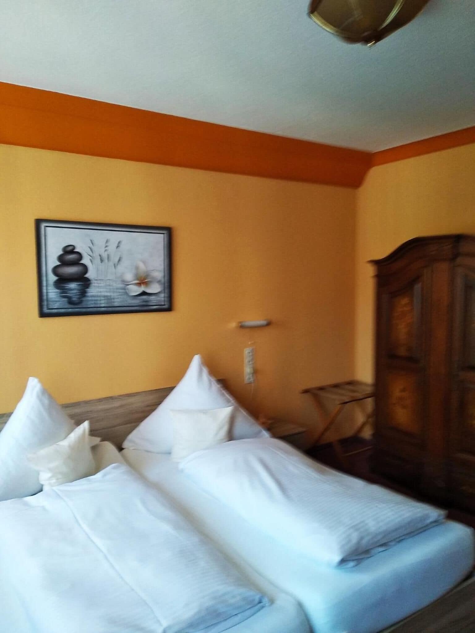 A room with a bed, a wooden cabinet, and a wall-mounted picture.
