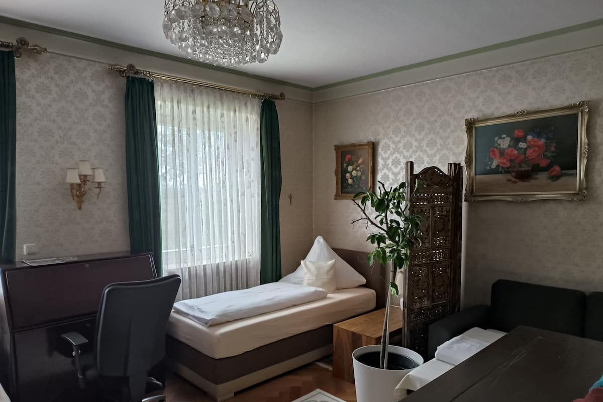 A hotel room with a bed, desk, chair, and a large window with curtains.