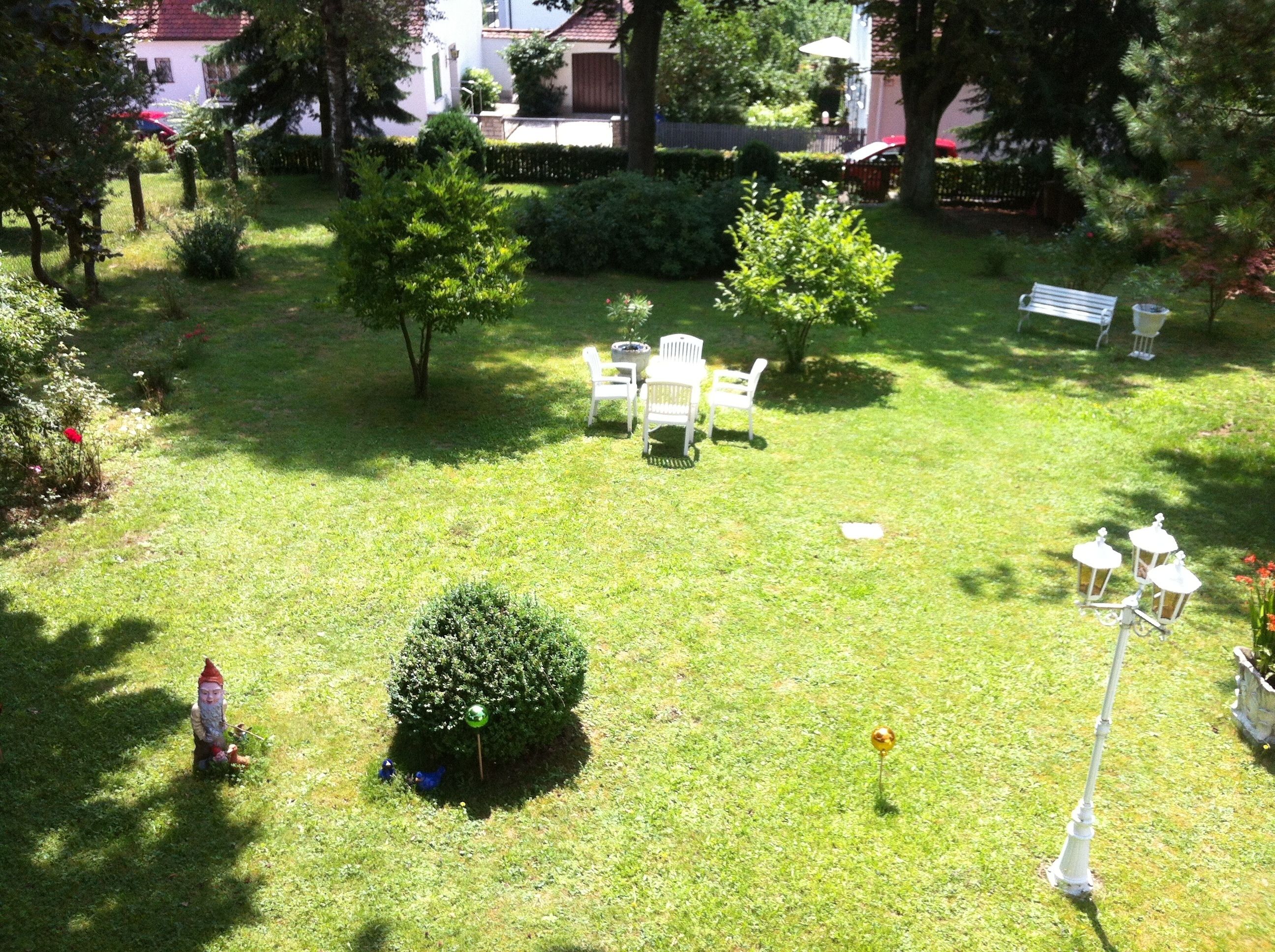 A well-maintained garden with a seating area, a small gnome statue, and a lamp post.