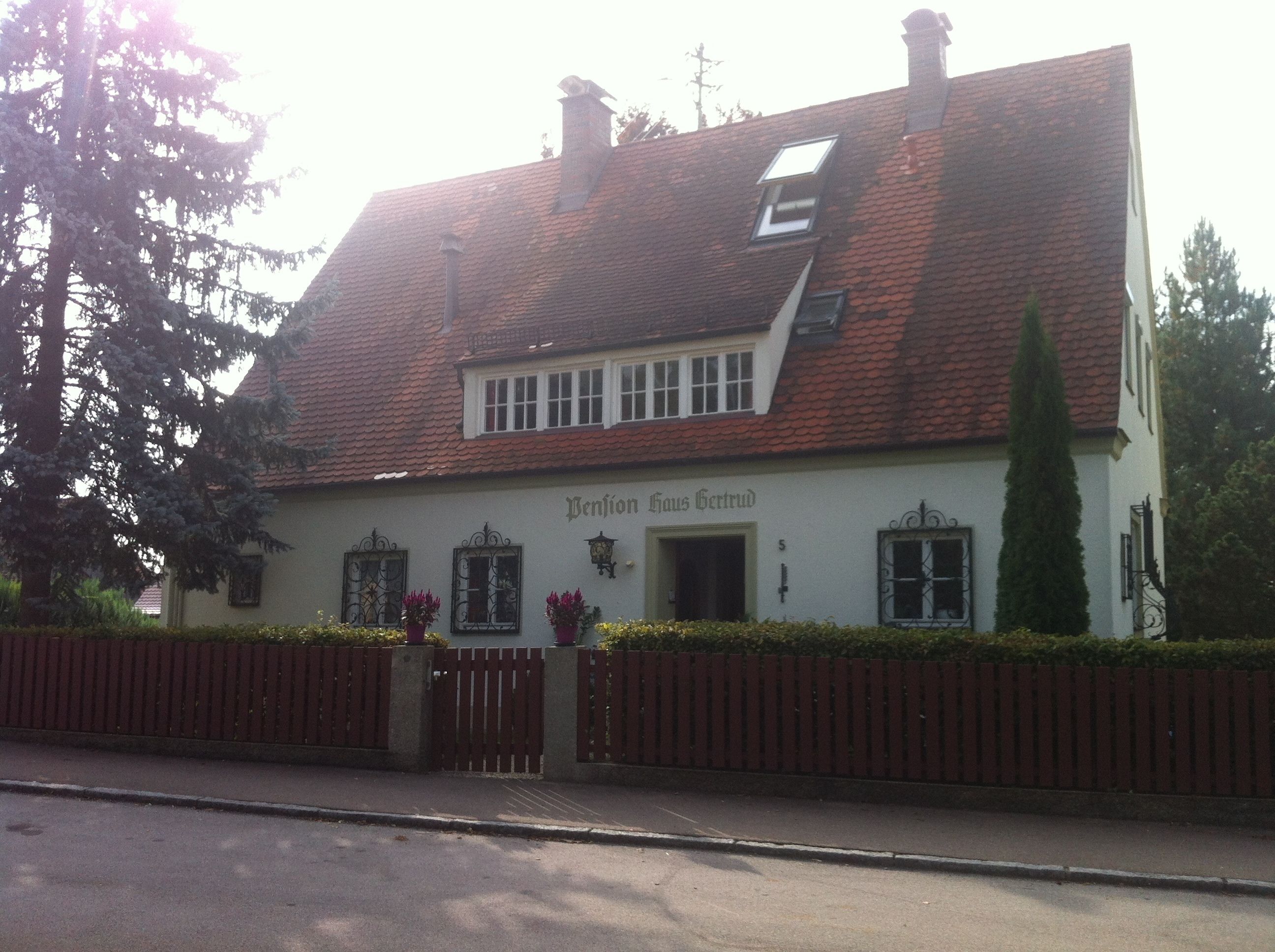A traditional building with a sloped roof, a small window with a white frame, and a sign that reads "Benjion Haus Gertrud".