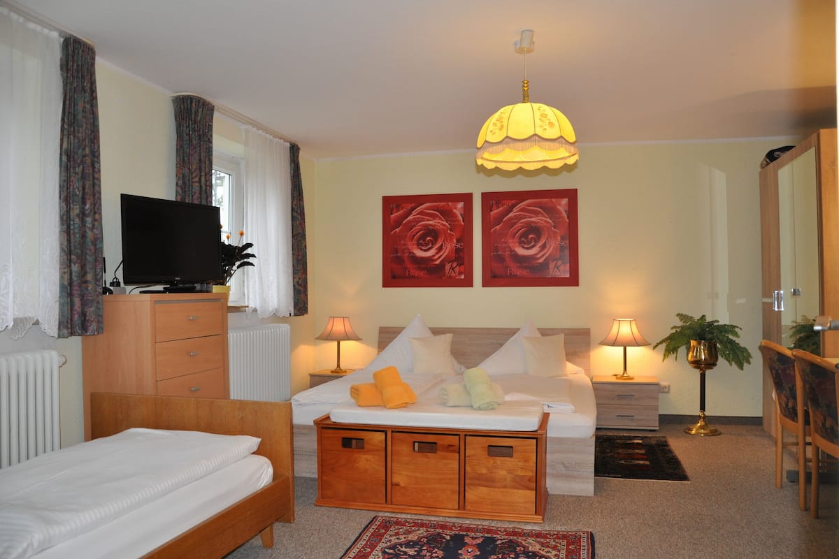 A bedroom with a bed, bedside tables, a TV, artwork, and a lamp.