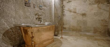 Un baño con una bañera antigua, ducha y pared con textura.