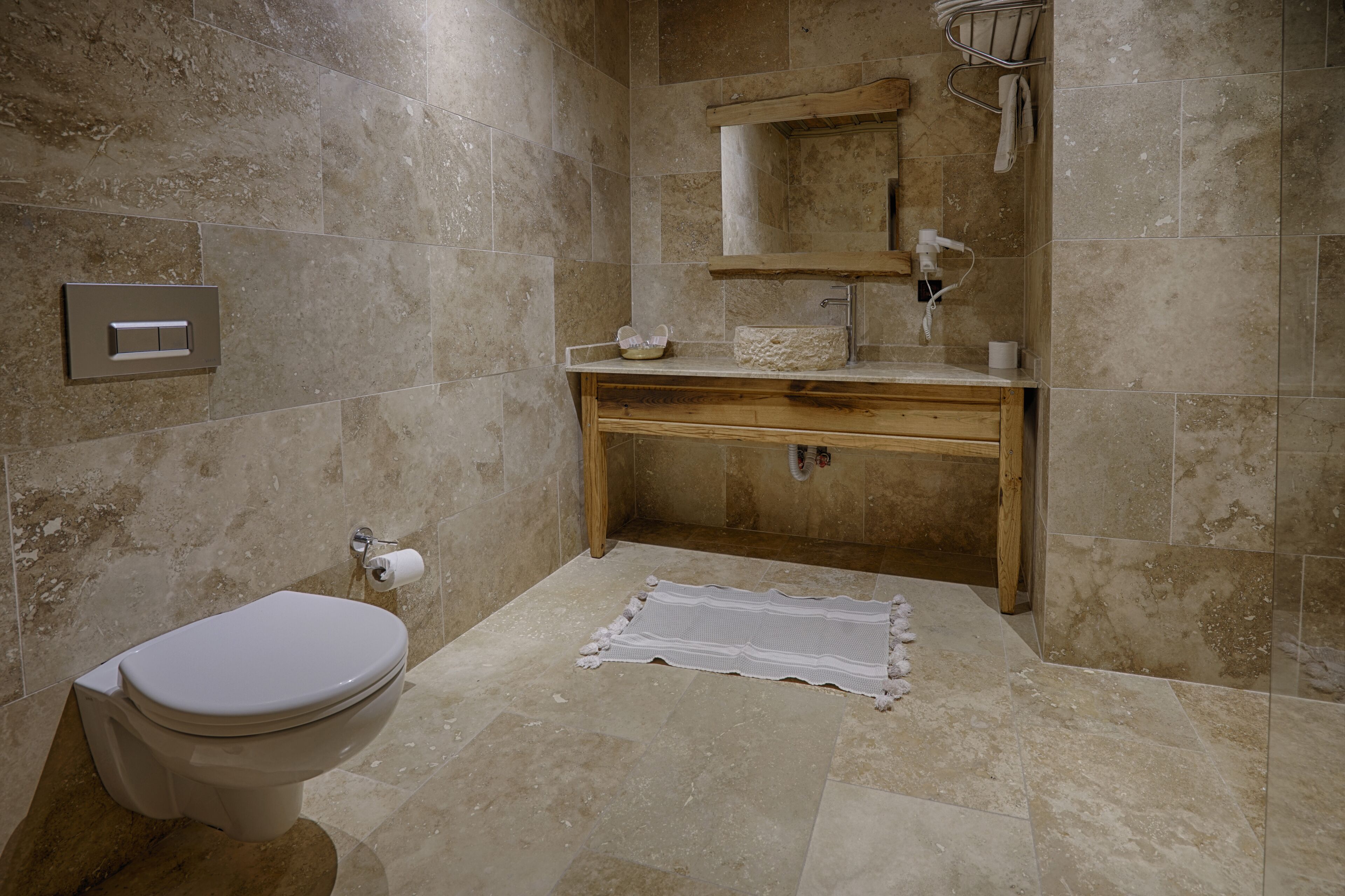 A bathroom with a toilet, sink, mirror, and shower area.
