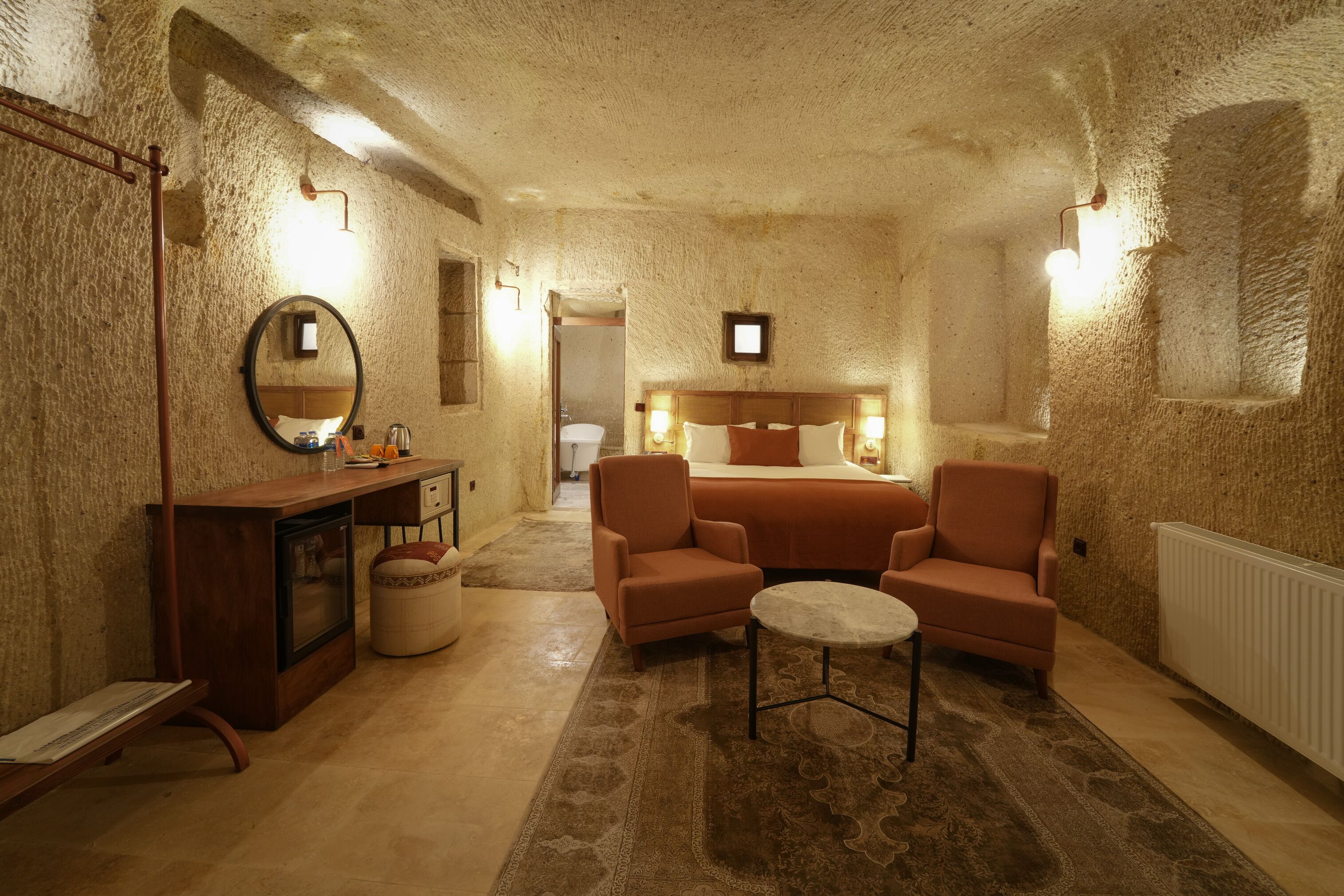 Une pièce confortable avec un lit, deux fauteuils, une petite table, un miroir et une commode.
