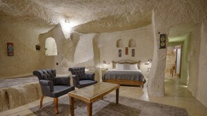 Una habitación con una cama, dos sillones, una mesa de centro de madera y una alfombra.