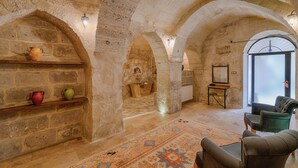 Habitación con paredes de piedra, chimenea, un sofá y un tapete estampado.
