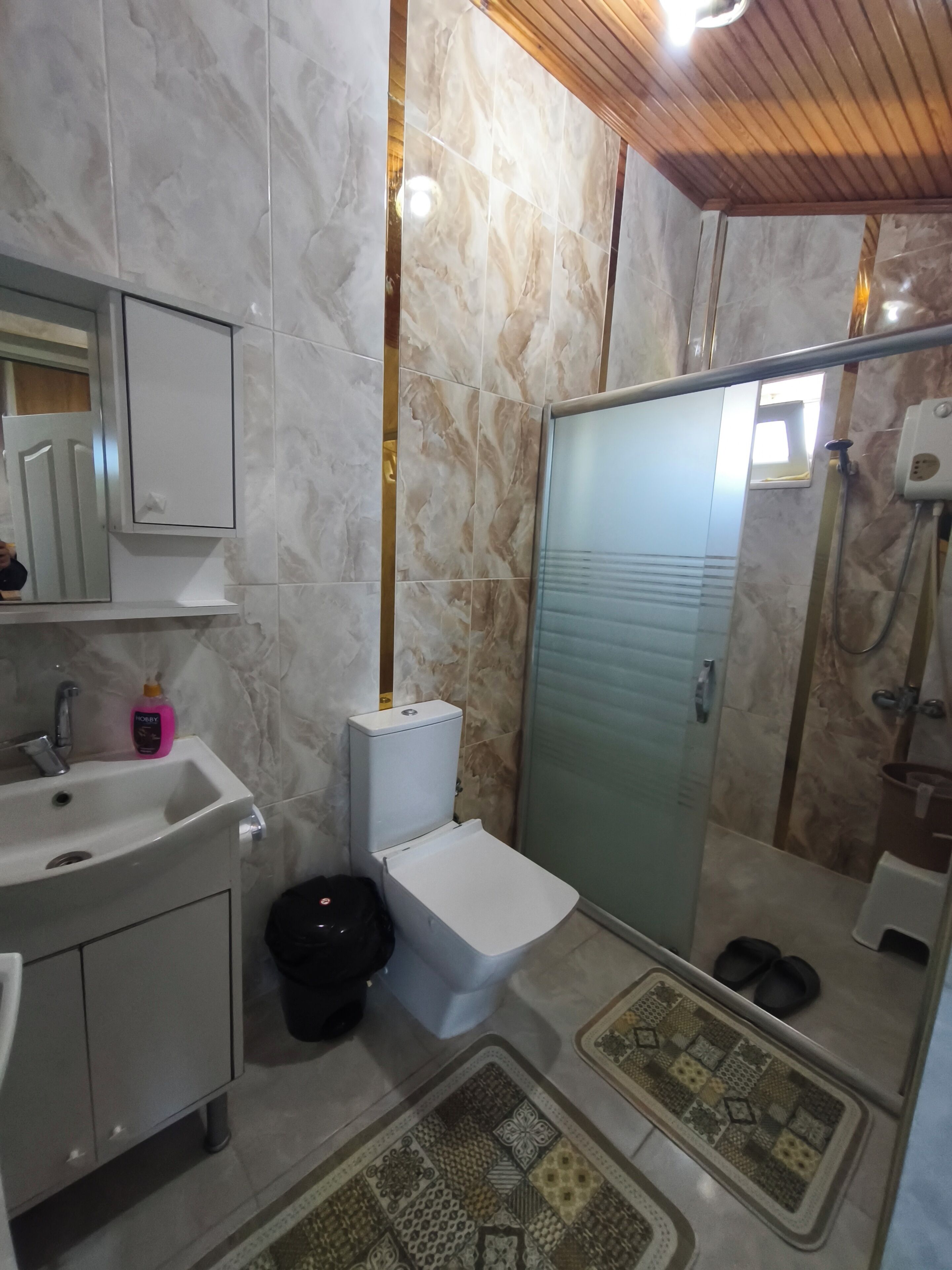 A bathroom with a toilet, sink, mirror, and shower.
