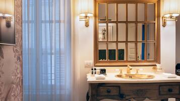 A bathroom with a large mirror, two wall-mounted lamps, a sink, and a vanity with drawers.