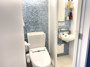 A bathroom with a toilet, sink, and shower. There are toiletries on a shelf. - Floral Hotel Sakaisujihonmachi Osaka (Osaka)