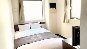 Ein Hotelzimmer mit Bett, Fernseher und einem Vorhangfenster.