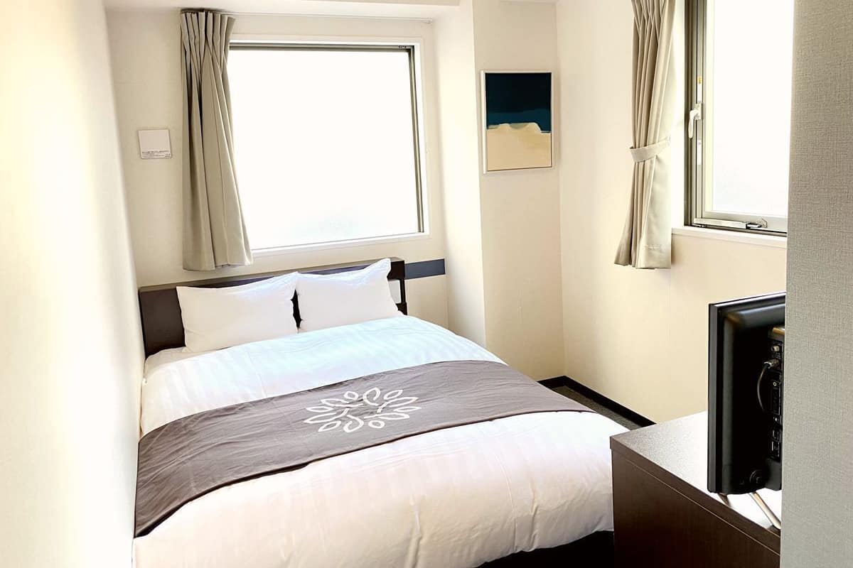 Une chambre d’hôtel avec un lit, une télévision et une fenêtre avec des rideaux.