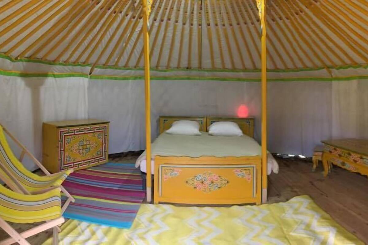 Una habitación con cama, una silla, una mesita y un armario.