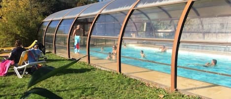 Una piscina al aire libre de temporada, sombrillas