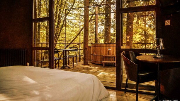 A bedroom with a large window, a bed, a table, and a chair. - Moulin de la Jarousse - Les Cabanes (Angoisse)