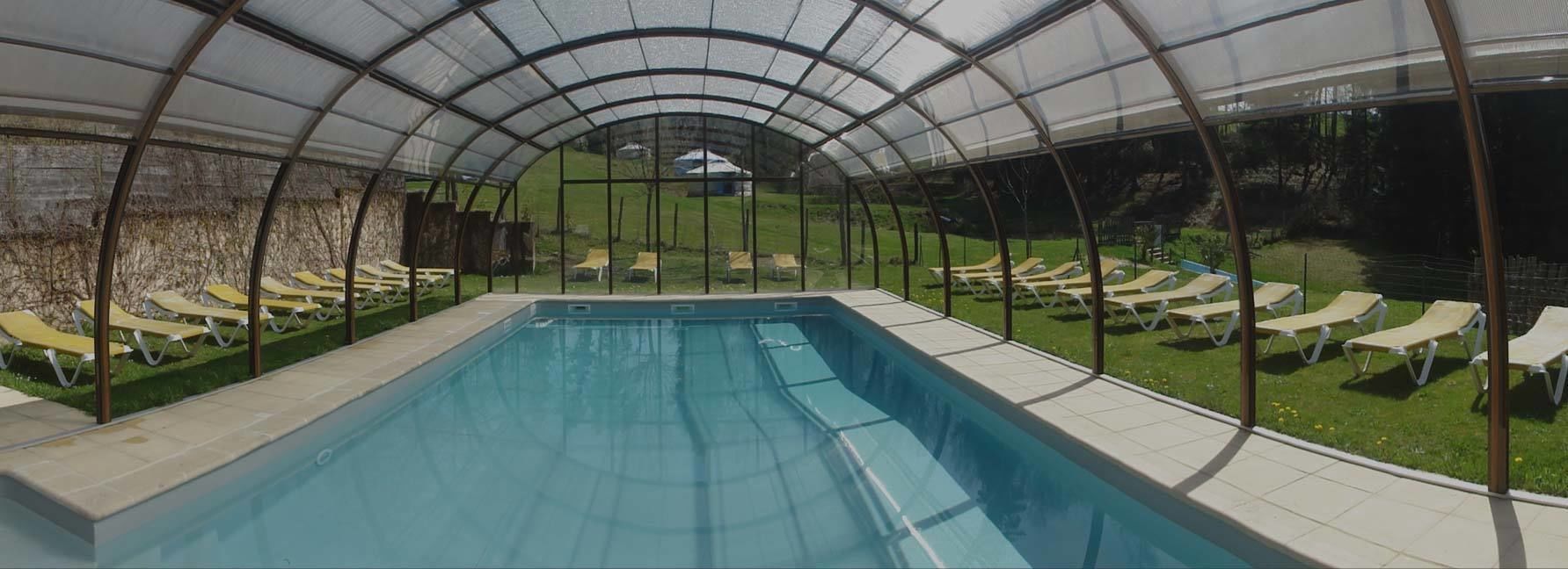 A covered swimming pool with lounge chairs and a view of the surrounding landscape.