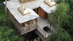 A wooden cabin with a balcony and a small deck area, surrounded by trees. - Moulin de la Jarousse - Les Cabanes (Angoisse)