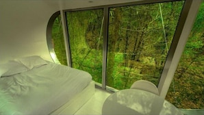A bedroom with a large window overlooking a forest. - Moulin de la Jarousse - Les Cabanes (Angoisse)