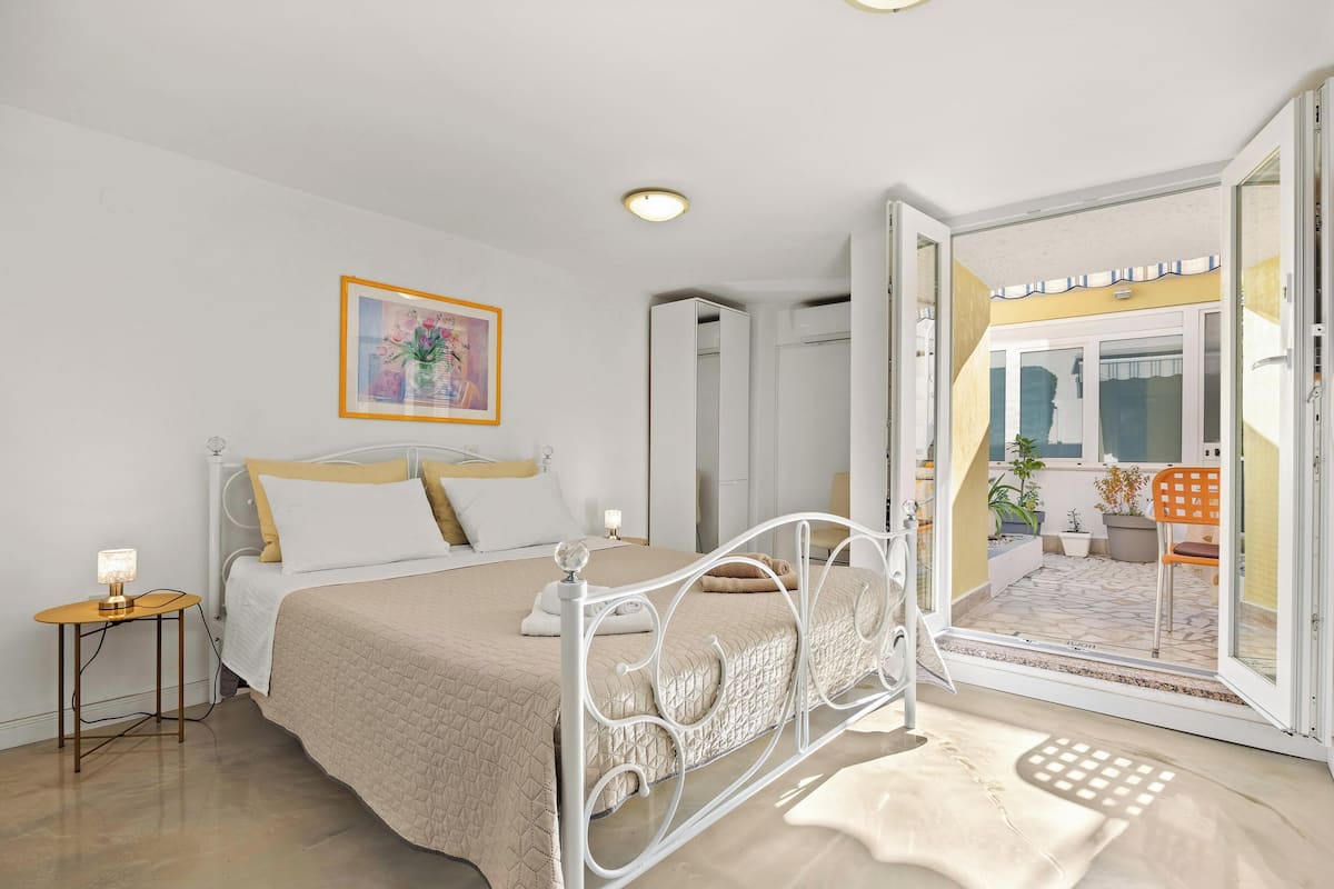 A bedroom with a bed, bedside table, and a view of the outdoor patio.