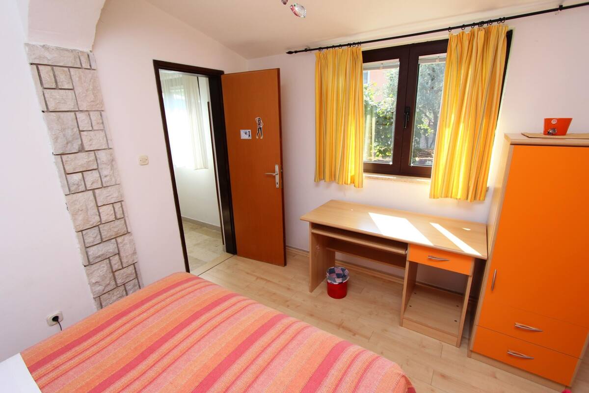A bedroom with a bed, a desk, and a wardrobe.