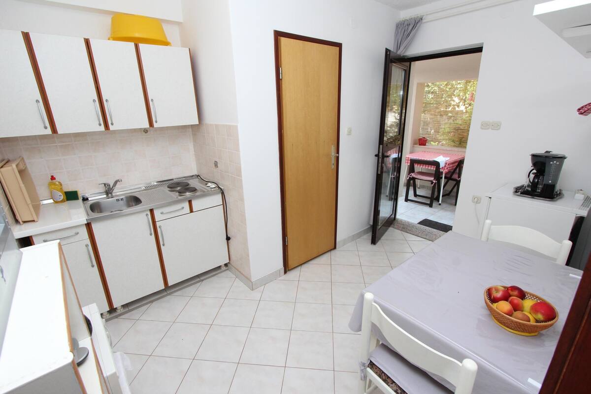 A compact kitchen with white cabinets, a sink, and a dining area with a table and chairs.
