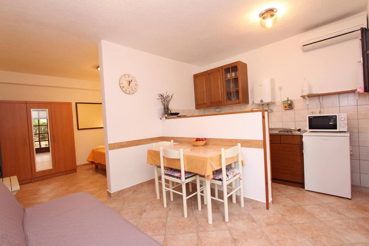 A compact kitchen with a dining table, chairs, a microwave, and a refrigerator.