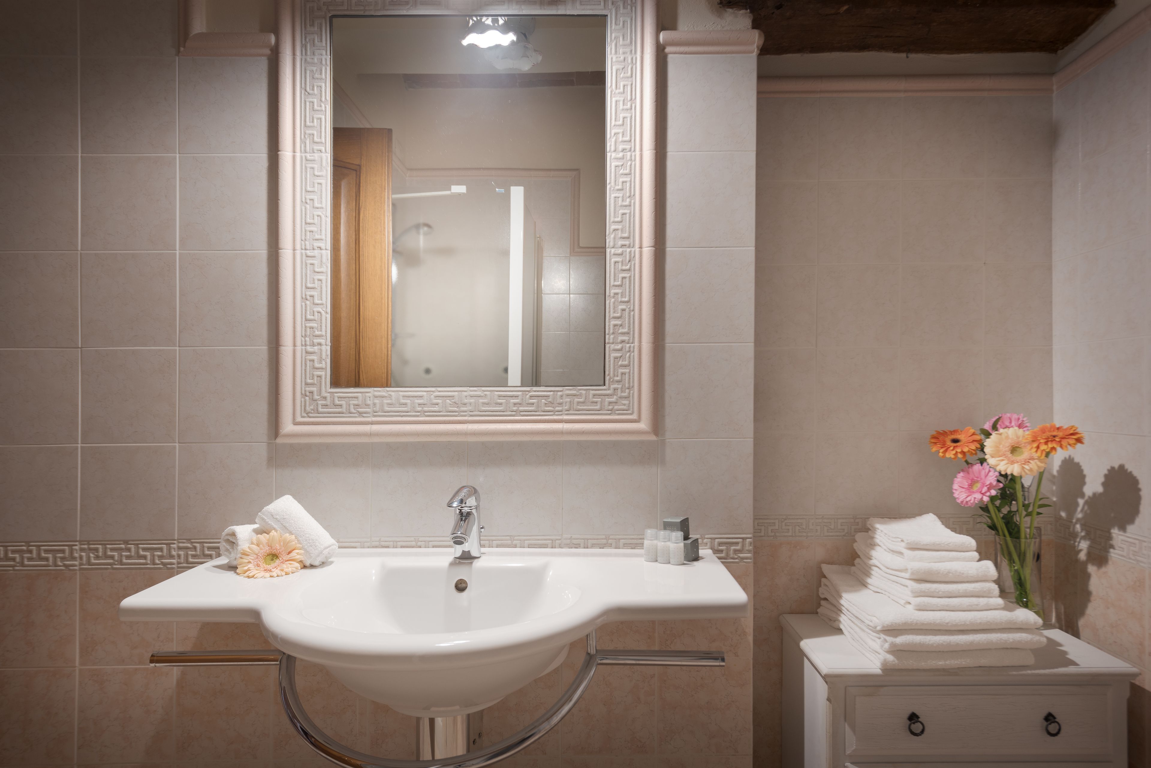 A bathroom with a white sink, mirror, and a stack of towels.