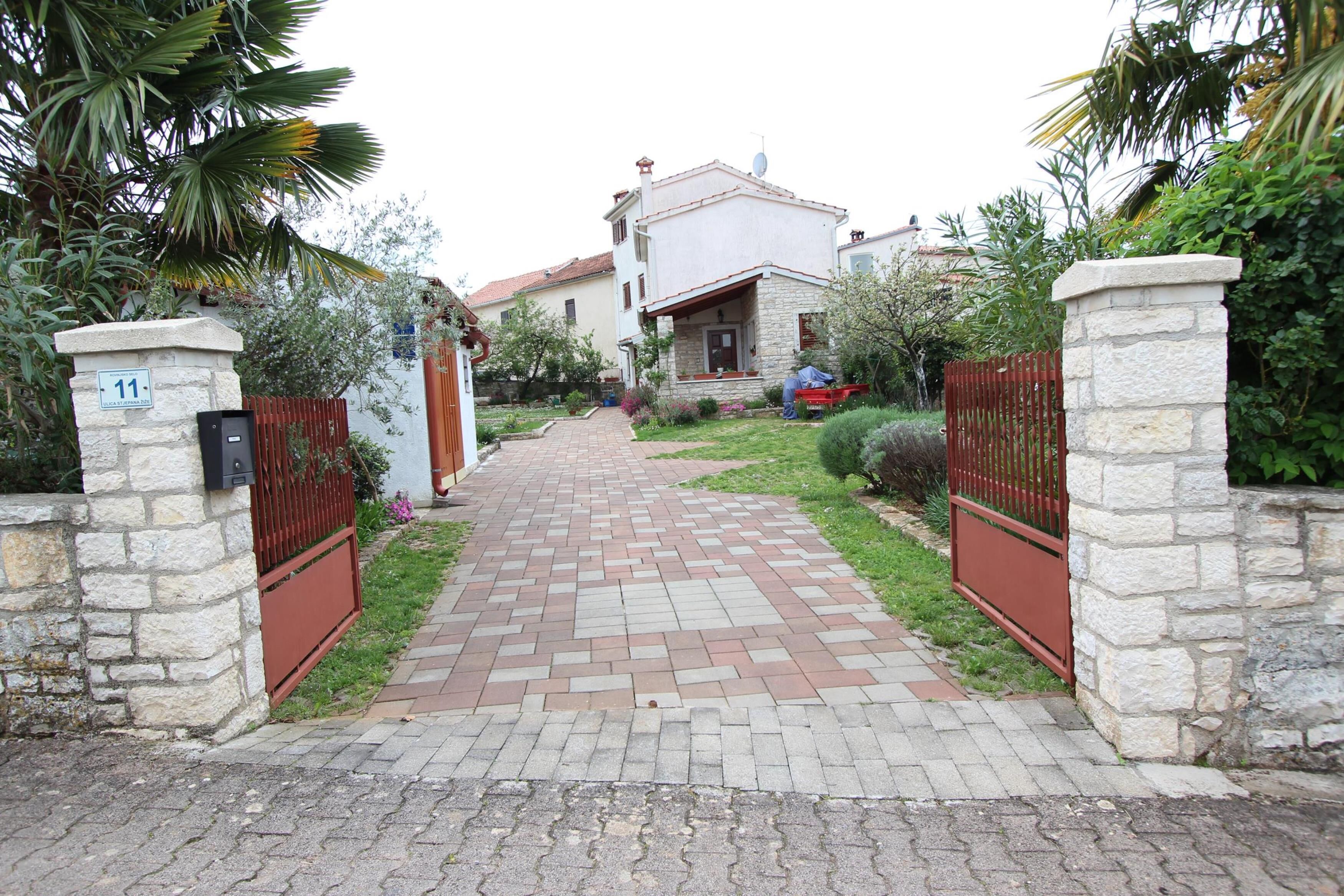 Un camino empedrado que lleva a una casa con un portón de piedra y el número 11.