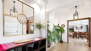 Een modern interieur met een houten console tafel, een grote spiegel en een eethoek op de achtergrond.