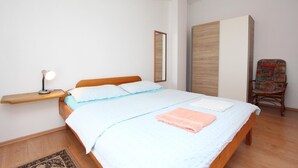 Une chambre à coucher comprenant un lit, une table de chevet, une chaise et un miroir.