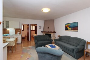 A living room with a sofa, a coffee table, and a fireplace. There is a dining area with a table and chairs.