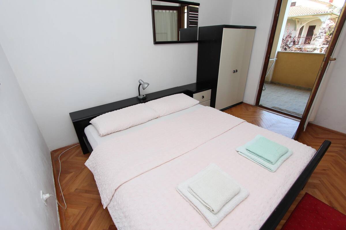 Ein Schlafzimmer mit Bett, Schreibtisch, Spiegel und Kleiderschrank.